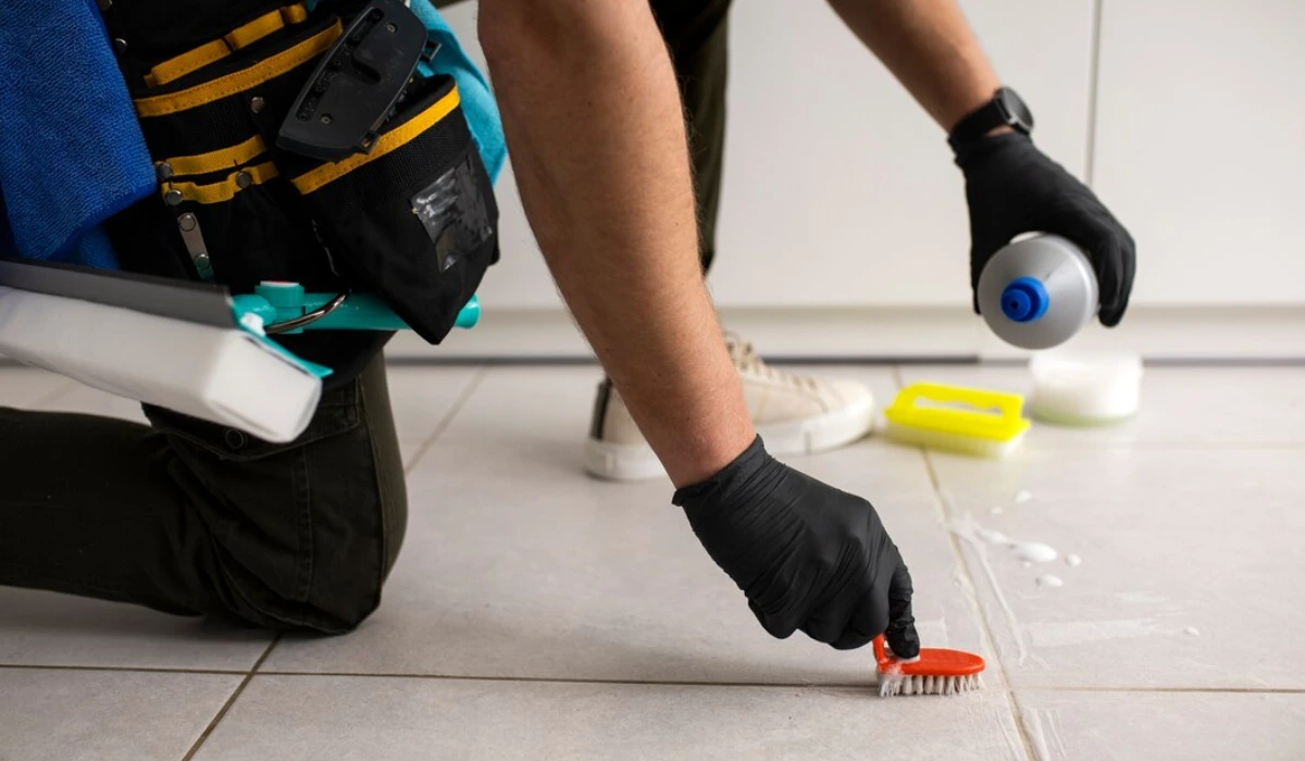 Grout cleaning in progress using a brush on tiled floor