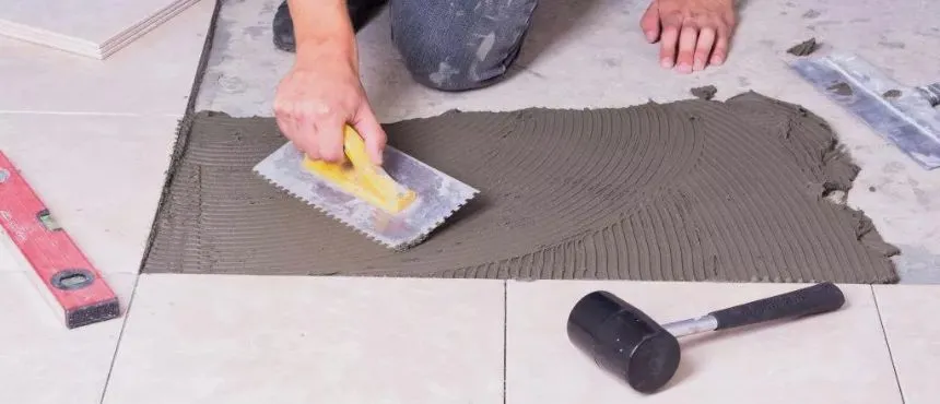 Professional technician performing tile floor installation and fixing with precision tools in Dubai.

