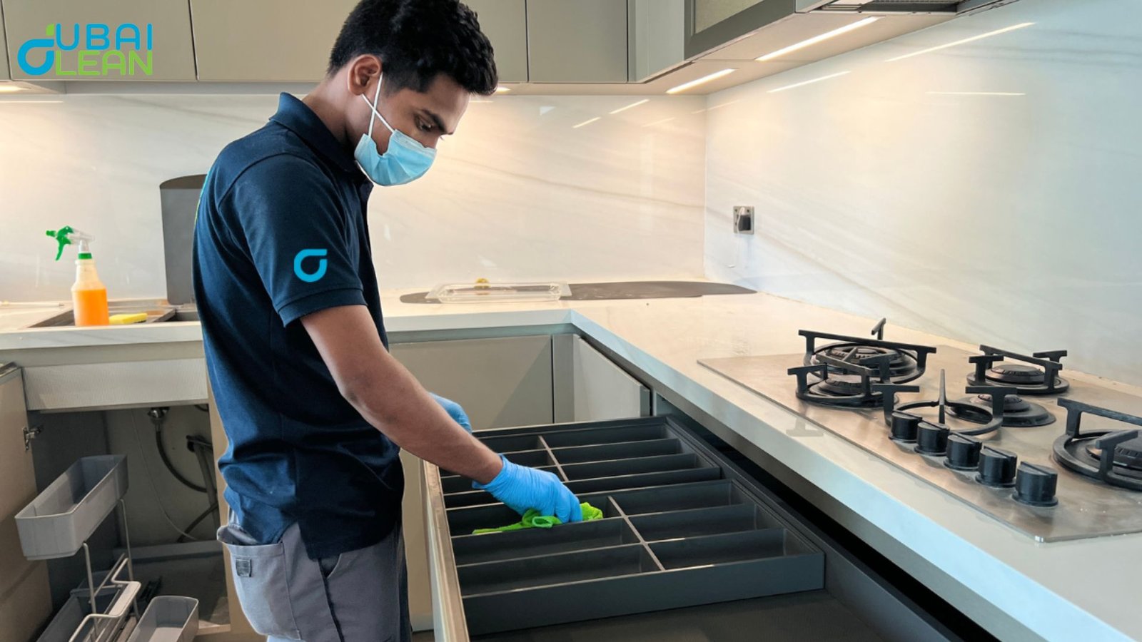 Modern kitchen cleaning setup with cleaning supplies and tools arranged on marble countertop in Dubai home